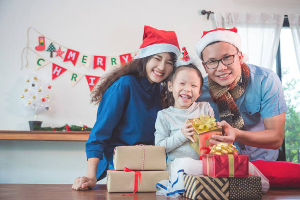 girl and her parents open christmas gift boxes at home stock photo