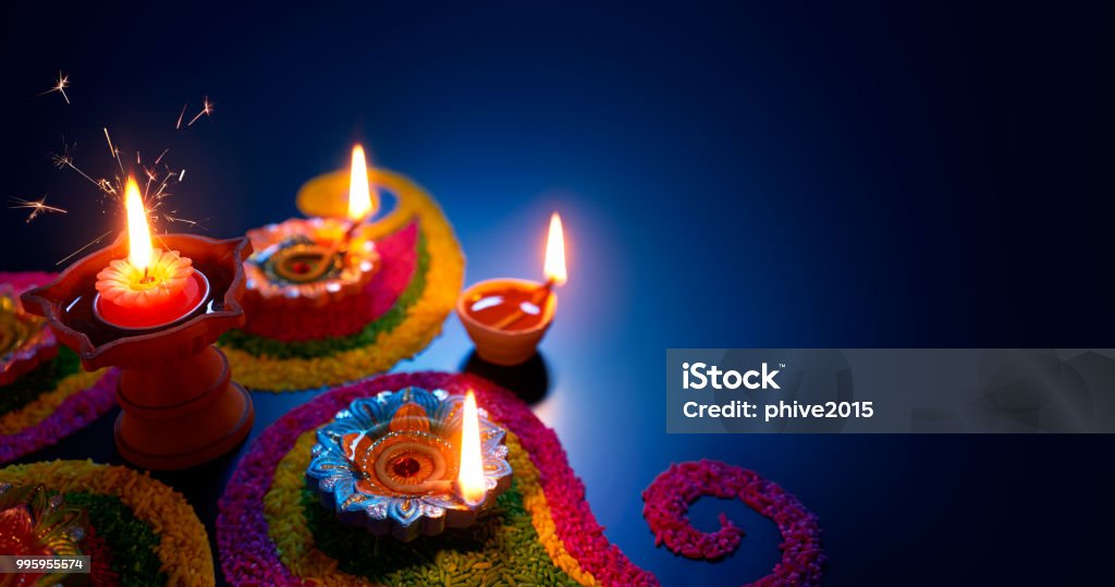 Oil lamps lit on colorful rangoli during diwali celebration Diwali Stock Photo