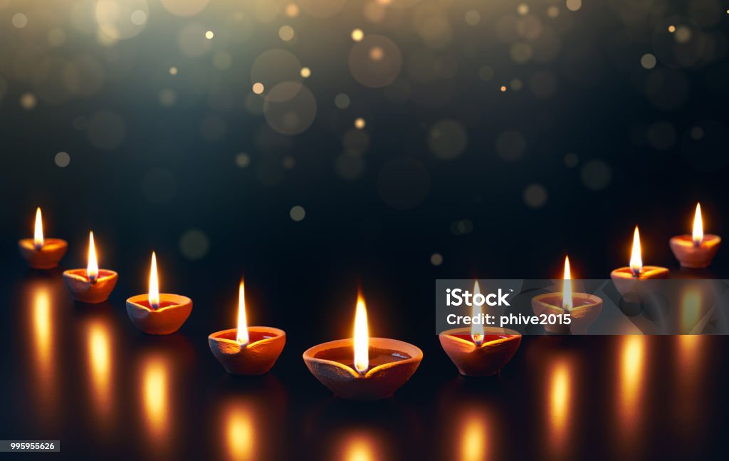 Diya lamps on a reflective base with glittering bokeh Diwali Stock Photo