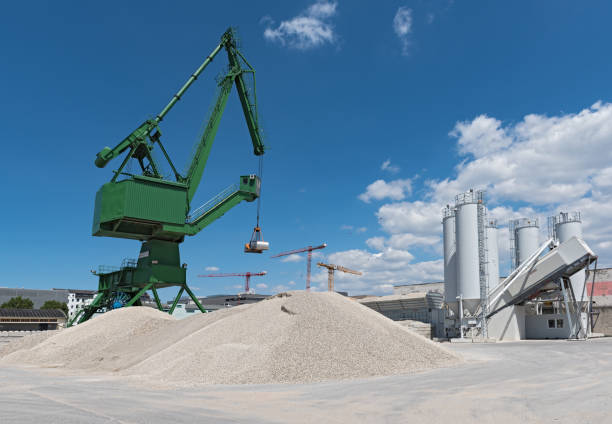 Exterior view of a cement factory with crane and concrete mixing silo Exterior view of a cement factory with crane and concrete mixing silo. cement work stock pictures, royalty-free photos & images