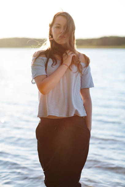 retrato: jovem mulher confiante na frente de um lago com costas iluminado - life back lit people happiness - fotografias e filmes do acervo