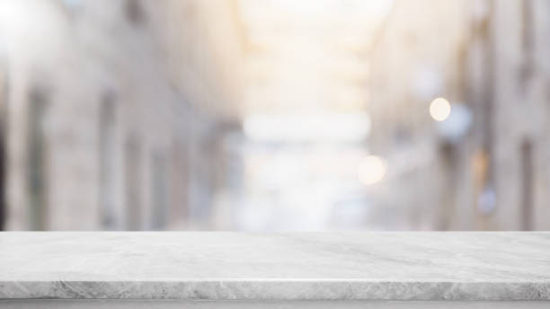 istock Empty white stone marble table top and blurred abstract background from shopping mall background - can used for display or montage your products. 995974122