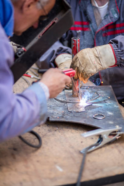 istock Welders in metal workshop welding wires. 995976970