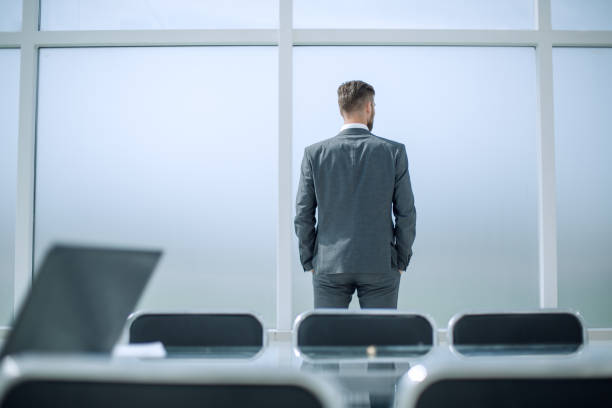 istock rear view.businessman looking in the office window 995982886