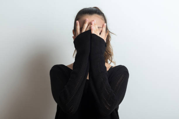 Young girl covers her face with her hands