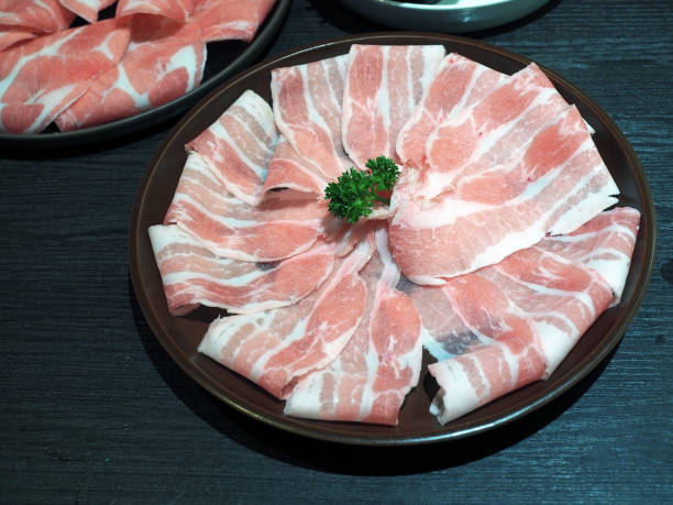 istock Plate of thin sliced pork meat (bacon) with chopsticks. 995986666