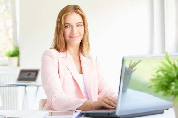 young professional woman using laptop while working - multi tasking efficiency financial advisor business imagens e fotografias de stock