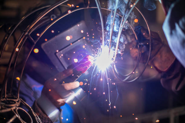 istock Two welders in metal workshop welding wires. 995991998