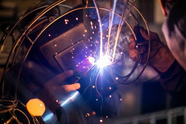 istock Two welders in metal workshop welding wires. 995992266