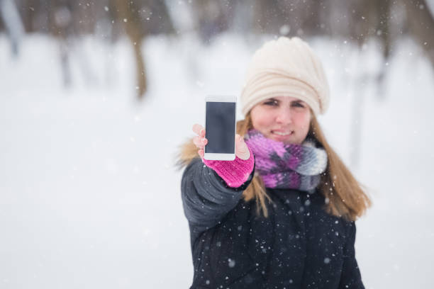 istock Beautiful female with smart phone. Winter scene. Space for copy. 995993240