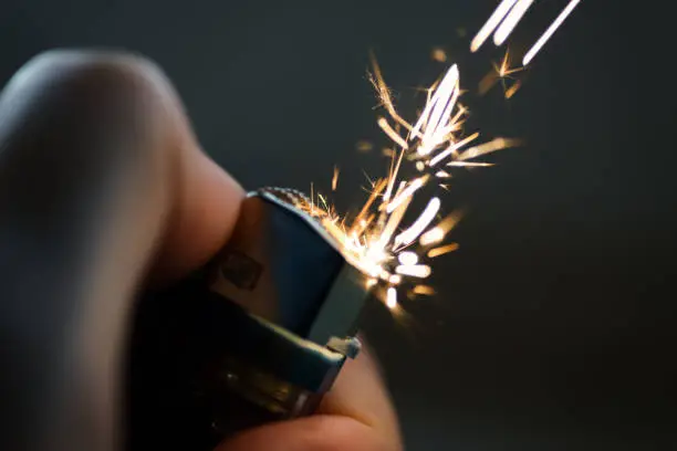 Lighters with flame sparking on dark background. Selective focus and shallow depth of field.