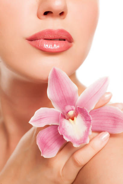 istock a pretty young woman with orchid on her shoulder on a white background 996006086