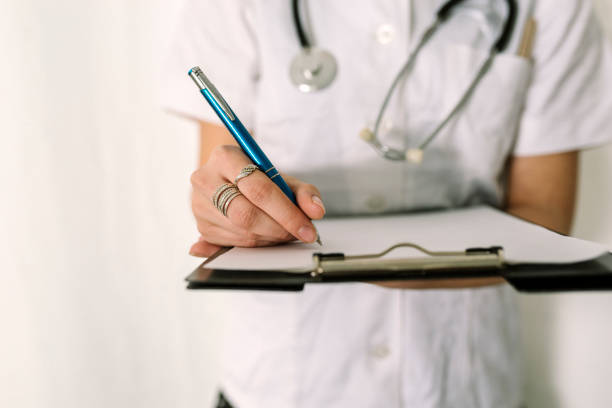 istock Young Female Doctor in White Medical Robe Holding a Folder 996016418