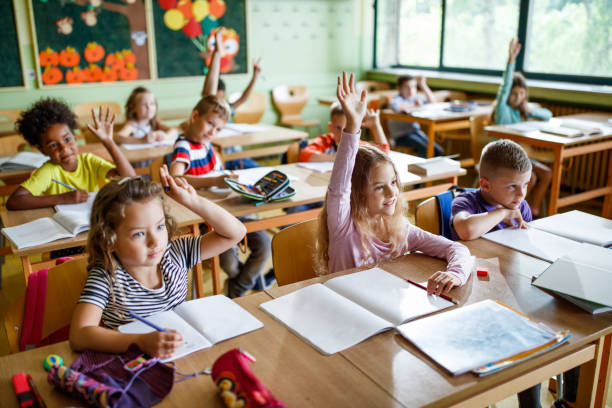 istock Group of happy elementary students raising their arms in the classroom. 996026718