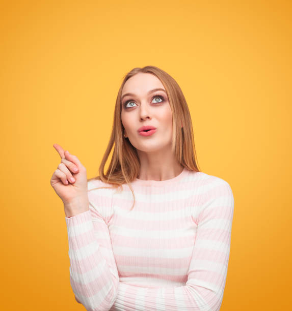 istock Woman pointing and looking up in studio 996028484