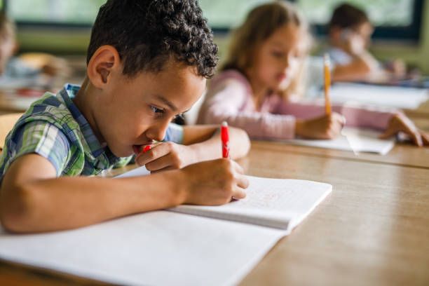 istock African American schoolboy writing a dictation during a class in elementary school. 996039400