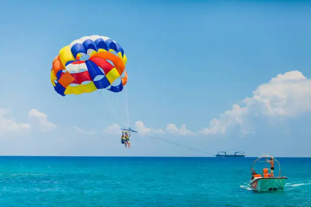 Parasailing water amusement - flying on a parachute behind a boat on a summer holiday by the sea in the resort