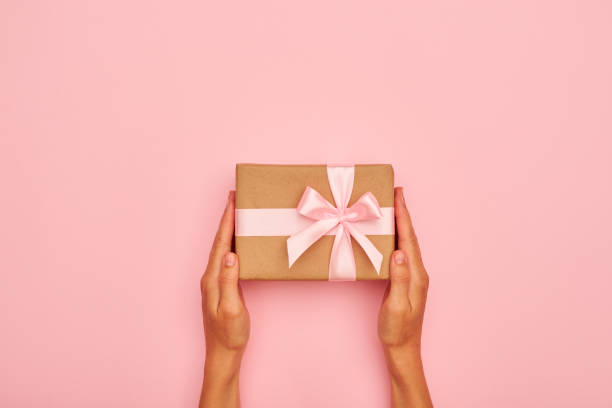 istock Hands holding beautiful gift box on pink flatlay 996055098