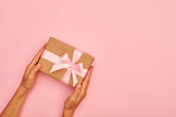 istock Hands holding cute gift box on pink flatlay 996055208