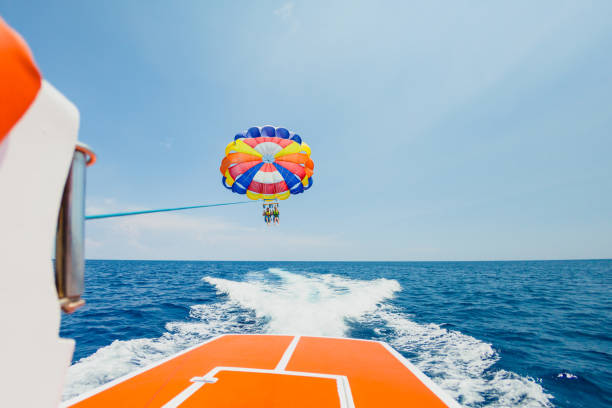 People flying on a colorful parachute towed by a motor boat stock photo