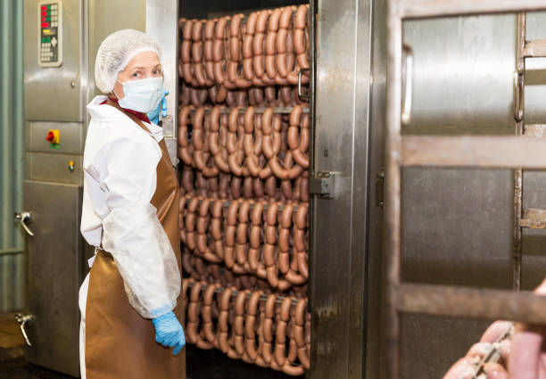 istock Female controlling hot processing of sausages 996073348