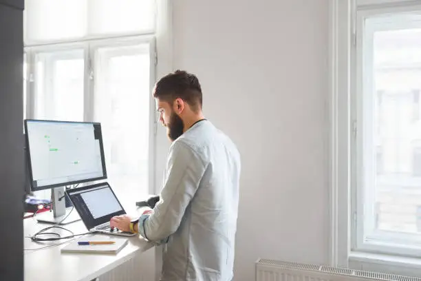 Photo of Young bearded man working at his office