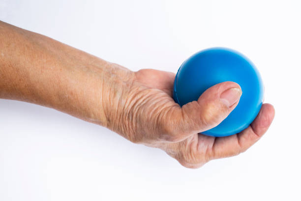 istock Senior woman's hand holding blue stress ball isolated on white background 996082270