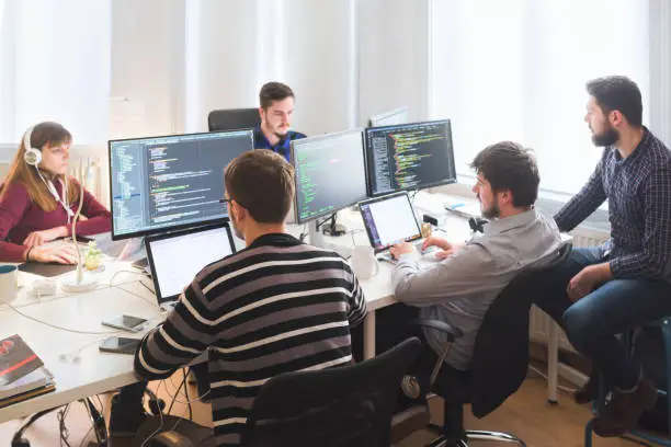 Group of software developers sitting at desktop computers being focused on their work