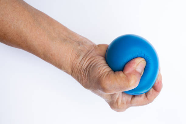 istock Senior woman's hand holding blue stress ball isolated on white background 996082970