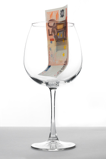 Fifty euro banknote inside a wine glass over a white background
