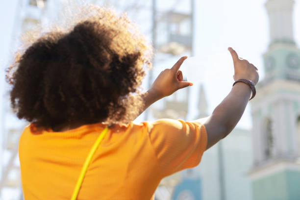 istock Curly-haired woman taking photos with transparent device 996092364