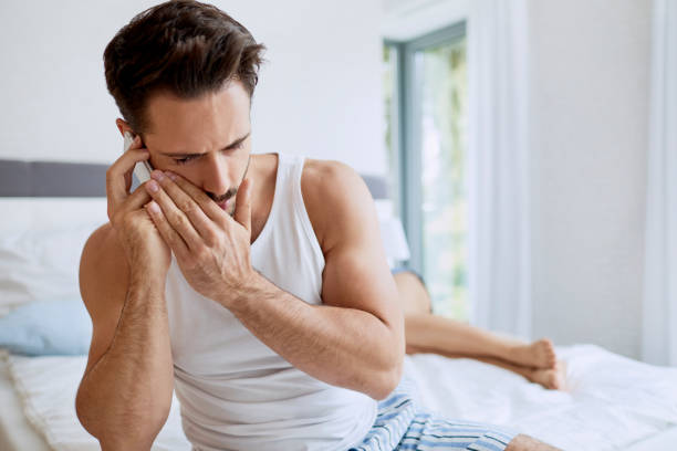 istock Man talking quietly on the phone while his girlfriend is sleeping in the background 996092422