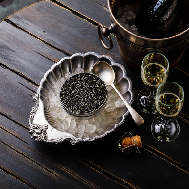 istock Black caviar in can on ice in silver bowl and champagne 996092838