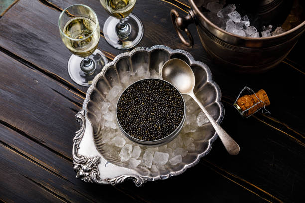 istock Black caviar in can on ice in silver bowl and champagne 996092862