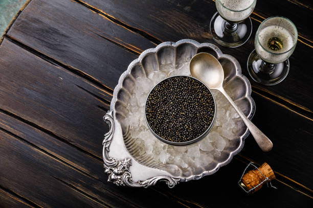 istock Black caviar in can on ice in silver bowl and champagne 996092864