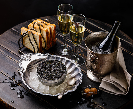 Caviar negro en poder en hielo en el tazón de plata, pan y champagne en cubo de hielo photo