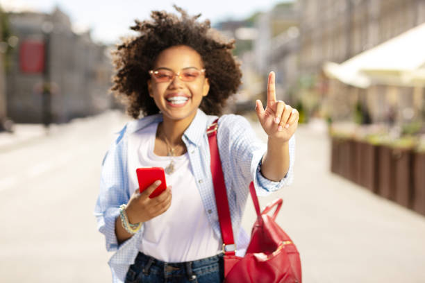 istock Charming woman raising her finger and using phone 996097206