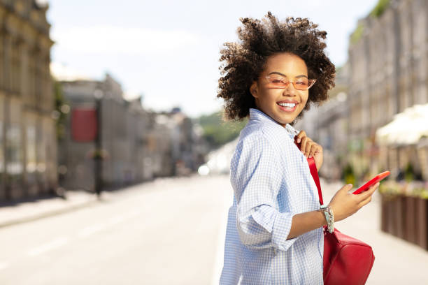 istock Cute curly woman posing while using phone in the streets 996097232
