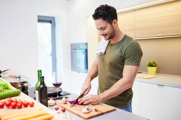 istock Handsome young man in the kitchen preparing vegetables for dinner 996100890