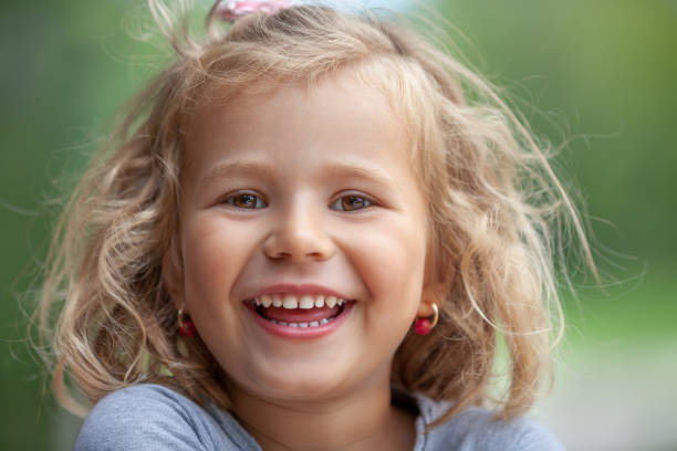 Smiling cute little girl on green trees background. This file is cleaned and retouched.