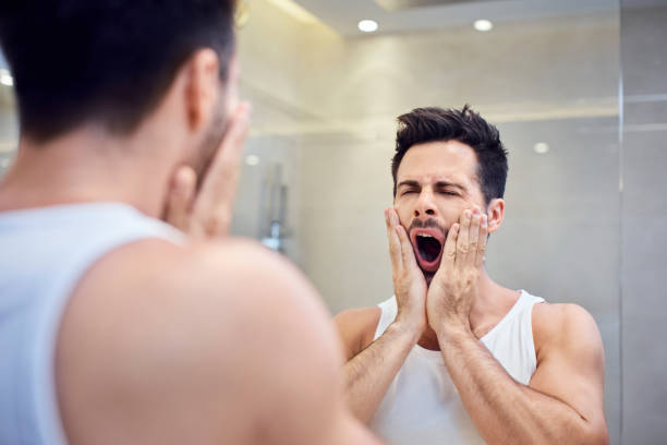 istock Sleepy young man standing in bathroom yawning 996105122