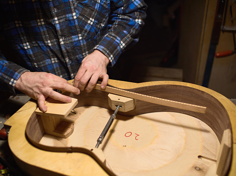 Glue lining to the side of the guitar. The process of making a classical guitar.
