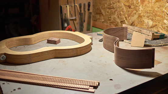 The process of making a classical guitar. shape for guitar, guitar side, lining, neckblock and tailblock on the table.