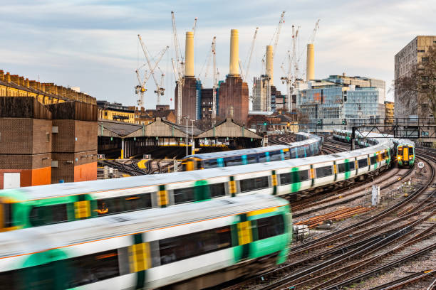 Trains on the tracks and power station on background in London Trains on the tracks and power station in London. Blurred trains leaving and arriving next a busy station. City background with buildings and construction in progress. Travel and transport concepts wandsworth photos stock pictures, royalty-free photos & images