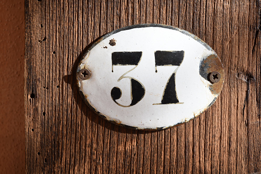 37 rusted old number plate against wooden background