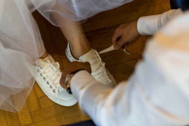 istock bridegroom helps the bride put her slippers and tie her. 996155316