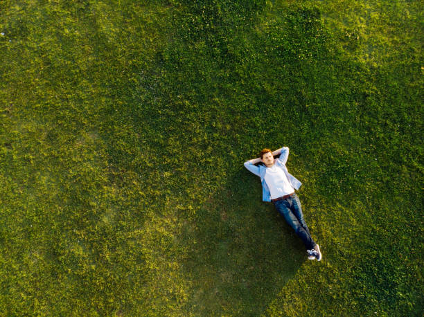 entspannte junger mann schlafen auf gras - überkreuzte beine stock-fotos und bilder