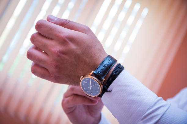istock a businessman touches and adjusts his luxury clock. 996159660