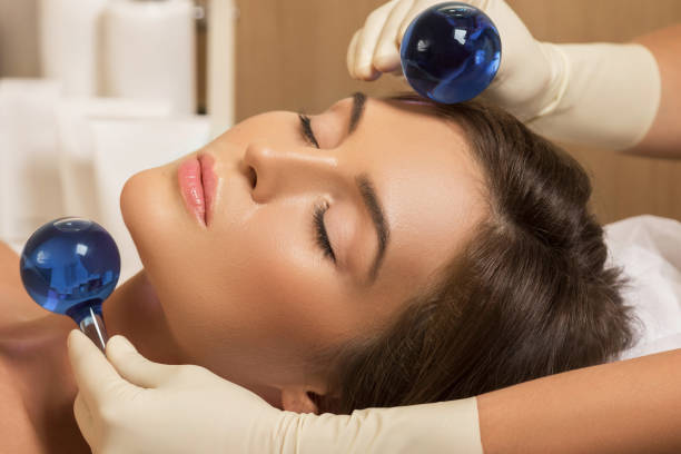 femme dans un salon de beauté pendant le traitement avec une boule en verre froid - massage ball photos et images de collection