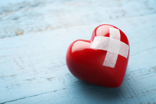 Red heart with adhesive bandage on blue wooden table